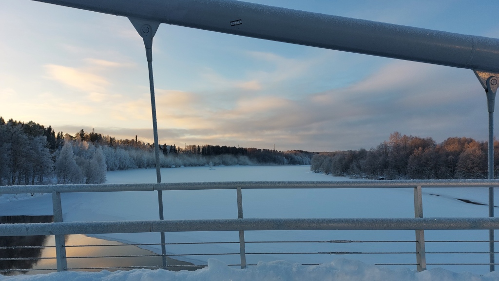 Wide, icy landscape. View from a bridge in Umea. Soft sunset in the background.